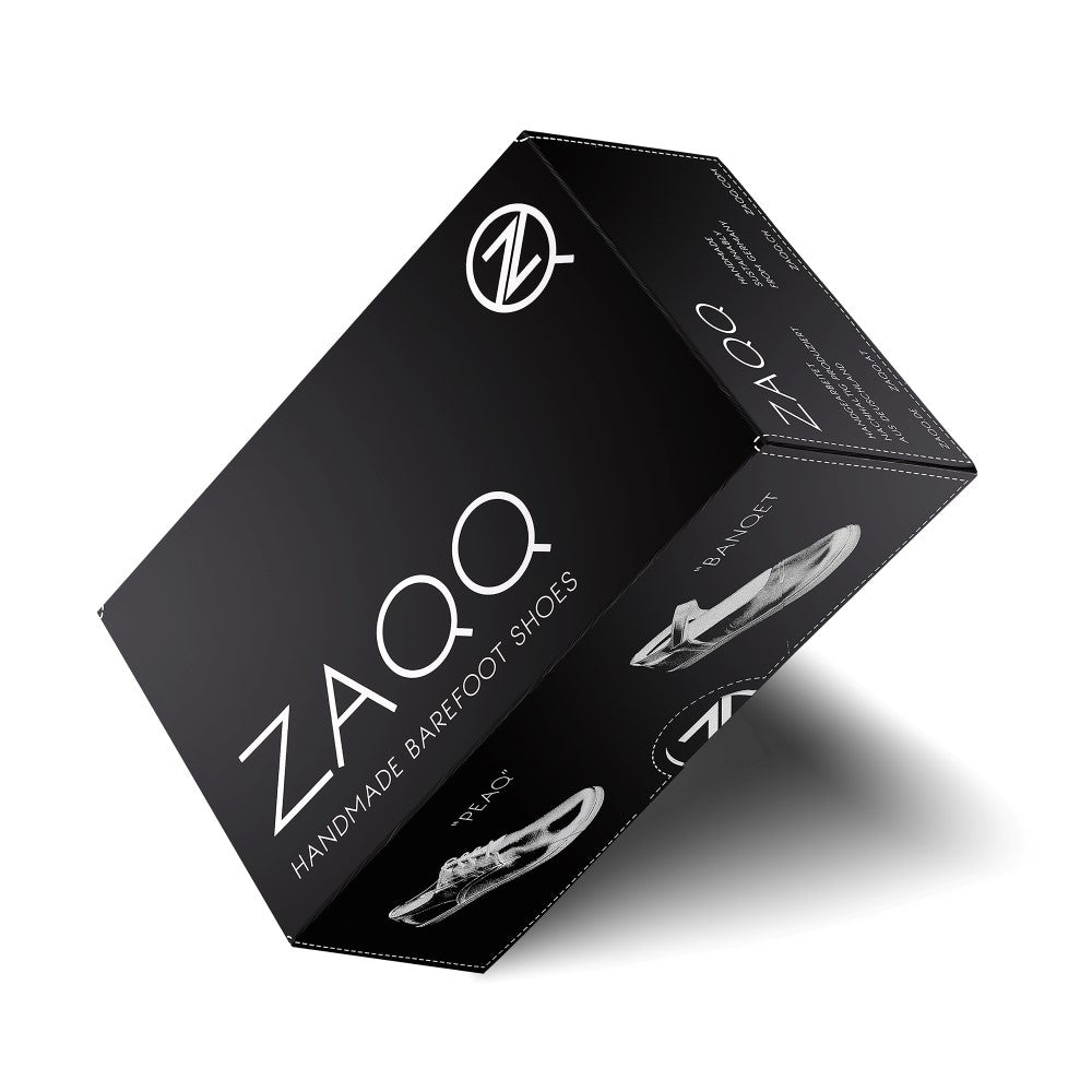 Una caja de zapatos negra con el logo de ZAQQ y la impresión en blanco "Handmade Barefoot Shoes" muestra el diseño dinámico de las elegantes zapatillas SPARQ High Pinatex. En diferentes lados se ven imágenes de un zapato y el logo de la marca, lo que subraya la artesanía única.