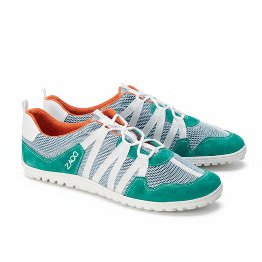 Wir präsentieren die RIQ Turquoise Sneaker von ZAQQ, ein lässiges Design mit blaugrünem und weißem Mesh-Gewebe, das für seine Atmungsaktivität bekannt ist. Diese Schuhe sind mit blaugrünem Wildleder akzentuiert, haben weiße, überkreuzte Schnürsenkel und ein auffälliges orangefarbenes Innenfutter. Der Markenname ZAQQ ist prominent an der Seite angebracht, während das Barfußschuh-Design mit strukturierten Gummisohlen für mehr Komfort ausgestattet ist.