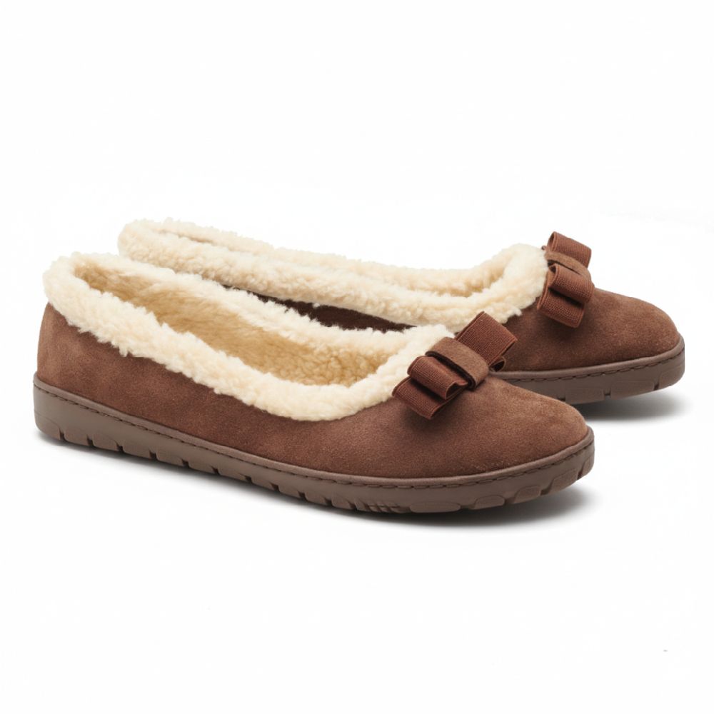 Der DAQIN Winter Brown von ZAQQ hat ein plüschiges, cremefarbenes Futter und dekorative Schleifen auf der Oberseite. Diese Slipper aus Veloursleder verfügen über eine flache, wildlederähnliche Textur und eine rutschhemmende Kautschuksohle für zuverlässigen Halt.