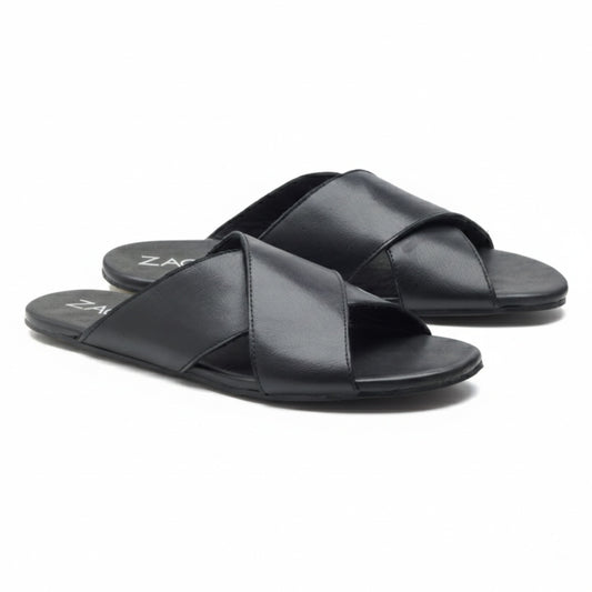 Ein Paar schwarze MANQA-Sandalen von ZAQQ aus feinem Nappaleder mit überkreuzten Riemen und flacher Sohle, elegant vor einem weißen Hintergrund präsentiert.
