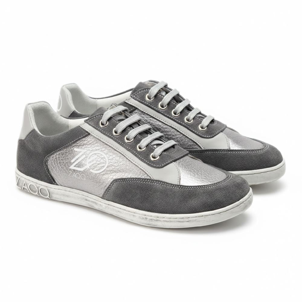 Ein Paar OQTAV Grey-Sneaker von ZAQQ, gefertigt aus samtigem Wildleder und strukturierten Einsätzen. Mit silbernen Schnürsenkeln und dem unverwechselbaren Zagoo-Logo an der Seite und der Ferse werden diese stilvollen Schuhe nebeneinander auf einem weißen Hintergrund präsentiert.