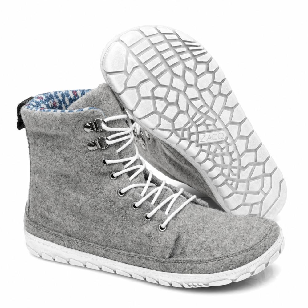 Se exhibe un par de zapatillas QICE Grey de caña alta de ZAQQ con cordones blancos. Un zapato está de pie mientras que el otro está inclinado para resaltar la suela exterior texturizada y con patrón.