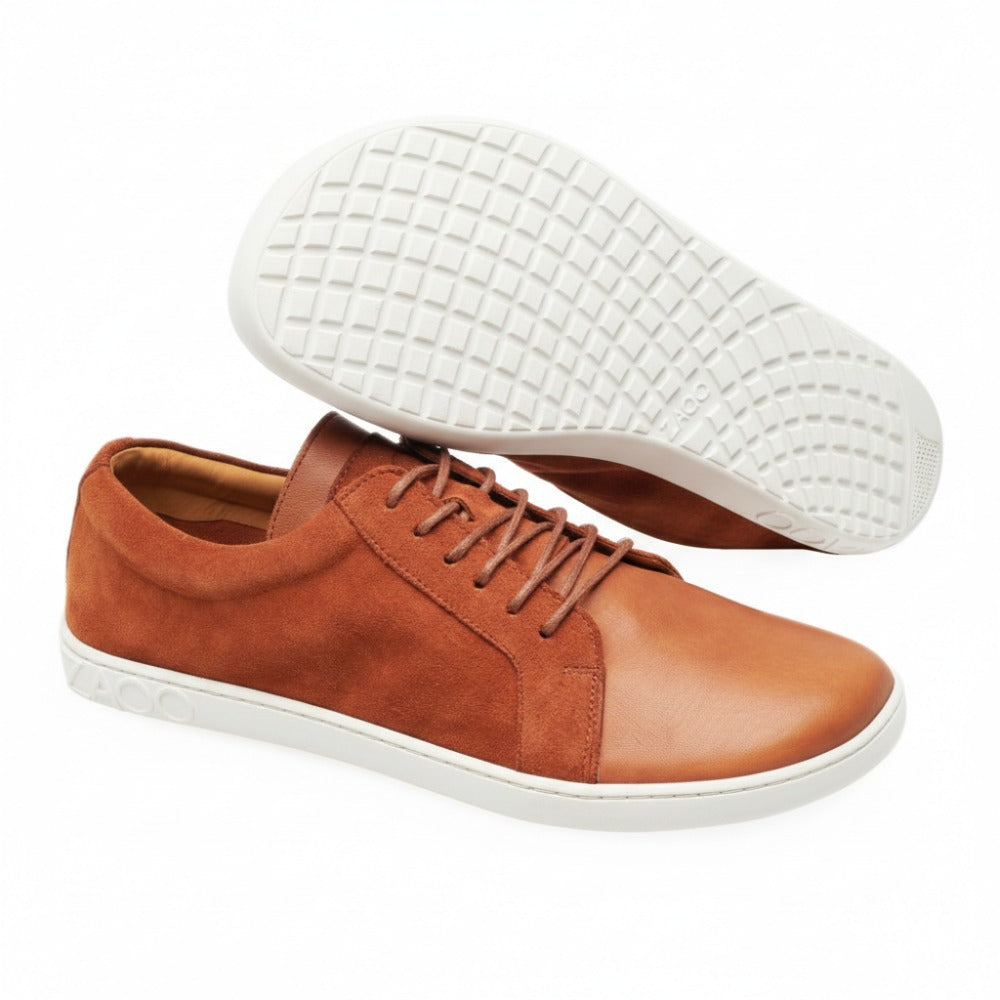 Die QORE Low Sierra Sneaker von ZAQQ bestehen aus einer Mischung aus braunem Wildleder und Leder mit grauen Gummisohlen. Ein Schuh steht aufrecht, während der andere die strukturierte Sohle freigibt.