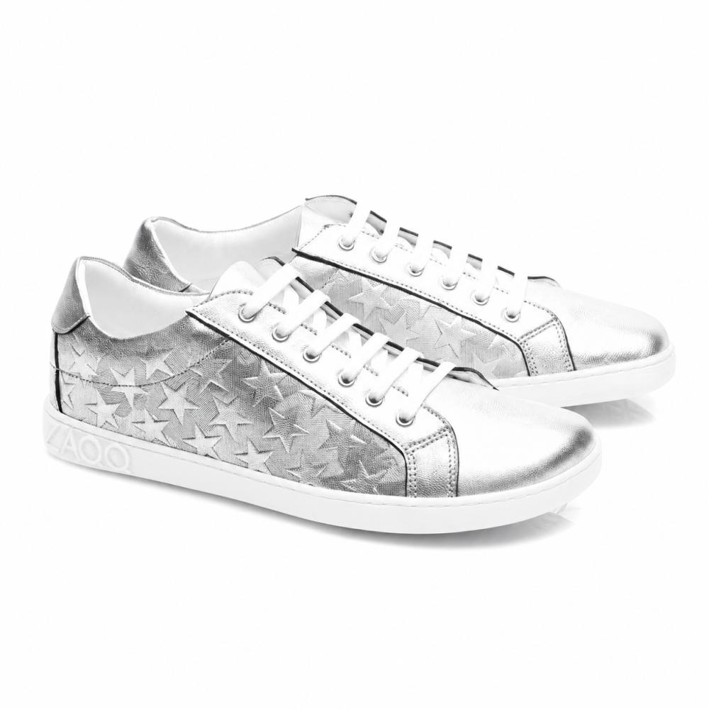 Las zapatillas SLOQ Stars Silver de ZAQQ tienen cordones blancos y un patrón de estrellas en los laterales, complementados con una suela blanca con grabado VAOO en el talón. Estos zapatos se destacan por un diseño elegante y moderno con un acabado metálico brillante.