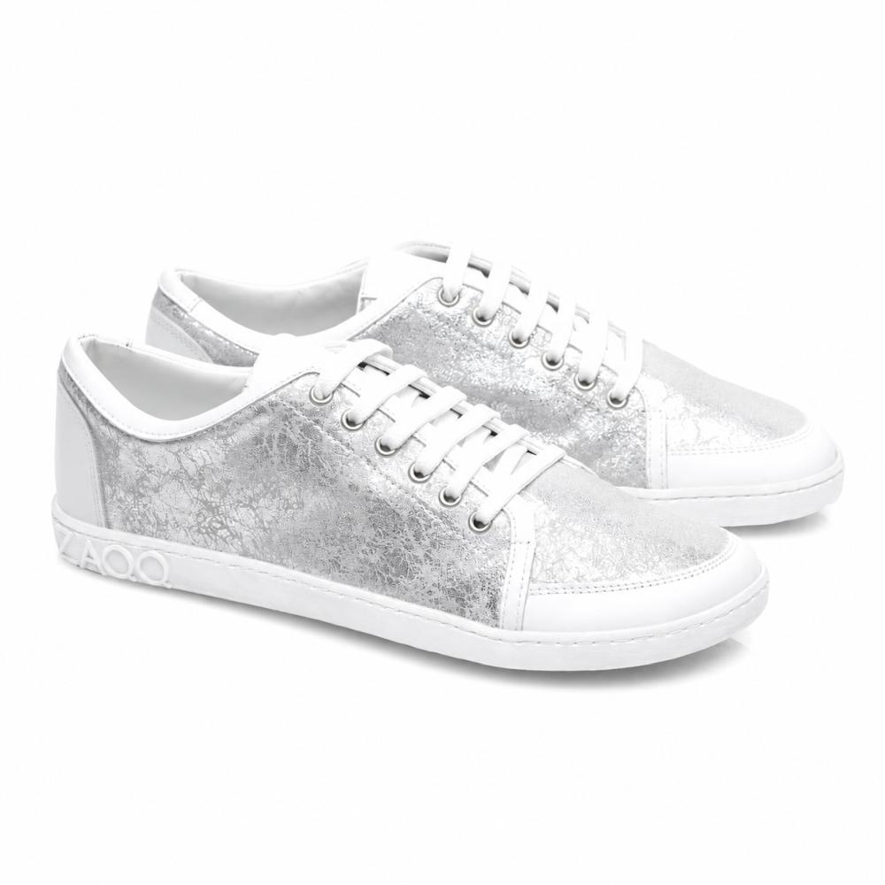 Presentamos el TIQQ Silver White de ZAQQ: Un par de zapatillas elegantes de napa de alta calidad con una textura metálica plateada llamativa y suelas blancas. Estas zapatillas están equipadas con cordones blancos brillantes, costuras decorativas y un distintivo detalle 4000 en el lateral de la suela.