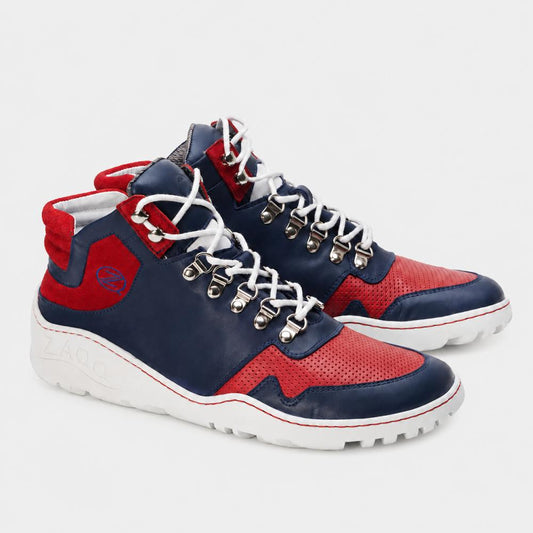 Wir präsentieren die wasserdichten VAQATION Red High-Top-Sneaker von ZAQQ. Diese stylischen Schuhe bestechen durch ein leuchtendes Rot, Marineblau und Weiß und sind mit der charakteristischen ZAQQ TERRA Sohle ausgestattet. Sie verfügen über weiße Schnürsenkel, Metallösen und perforierte Details auf den roten Abschnitten. Die weiße Außensohle ist mit strukturierten Griffen versehen, um die Traktion zu verbessern.