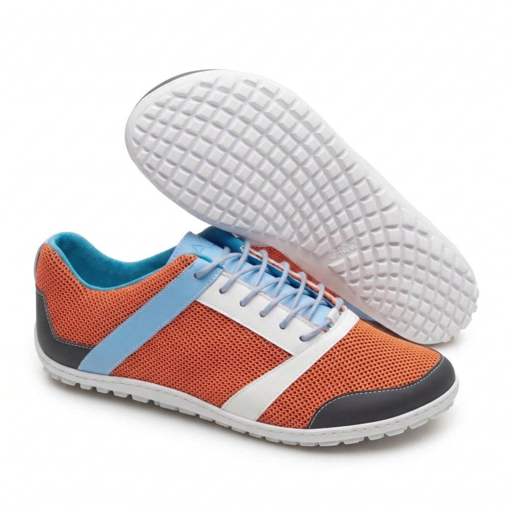 Ein Paar stylische ZARQA Orange von ZAQQ mit leuchtend orangefarbenem Netzgewebe, blauen Akzenten und weißen Schnürsenkeln. Die graue Sohle weist ein strukturiertes Muster auf. Ein Schuh steht aufrecht, während der andere auf der Seite liegt, wodurch das komplizierte Design der Sohle hervorgehoben wird.