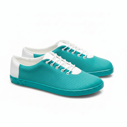 Wir präsentieren die QARO Heaven-Sneaker von ZAQQ in einem lebendigen türkisfarbenen Design mit eleganten weißen Akzenten und markanten sechseckigen Mustern. Diese Sneaker sind mit weißen Schnürsenkeln und weißen Abschnitten um den Knöchel für einen stilvollen Look ausgestattet. Die flexible Sohle ist ebenfalls türkis und ergänzt die Hauptfarbe dieser Schuhe perfekt.